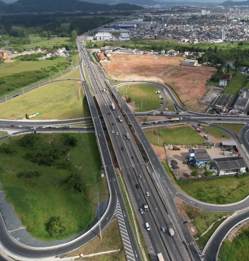 Vista aérea da rodovia litorânea ao lado do porto, com a ponte ao fundo